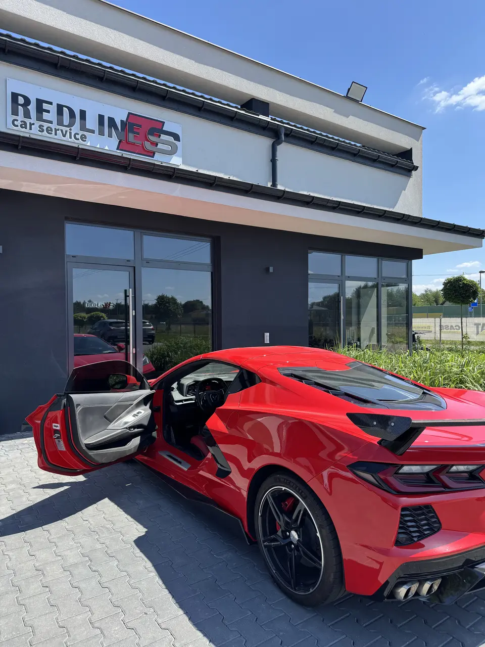 Czerwony Chevrolet Corvette C8 przed wejściem do Redlines Car Service