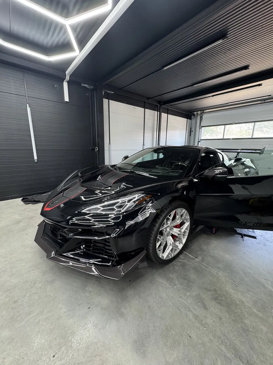 Czarny Chevrolet Corvette ZR1 w hali Redlines pod heksagonalnym oświetleniem
