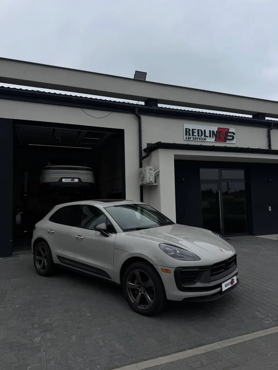 Srebrny Porsche Macan przed warsztatem Redlines Car Service